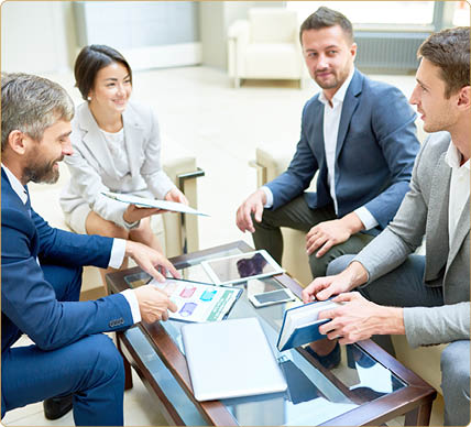 Group of successful business people working together at coffee table in modern office  focus on handsome young man talking to smiling colleagues